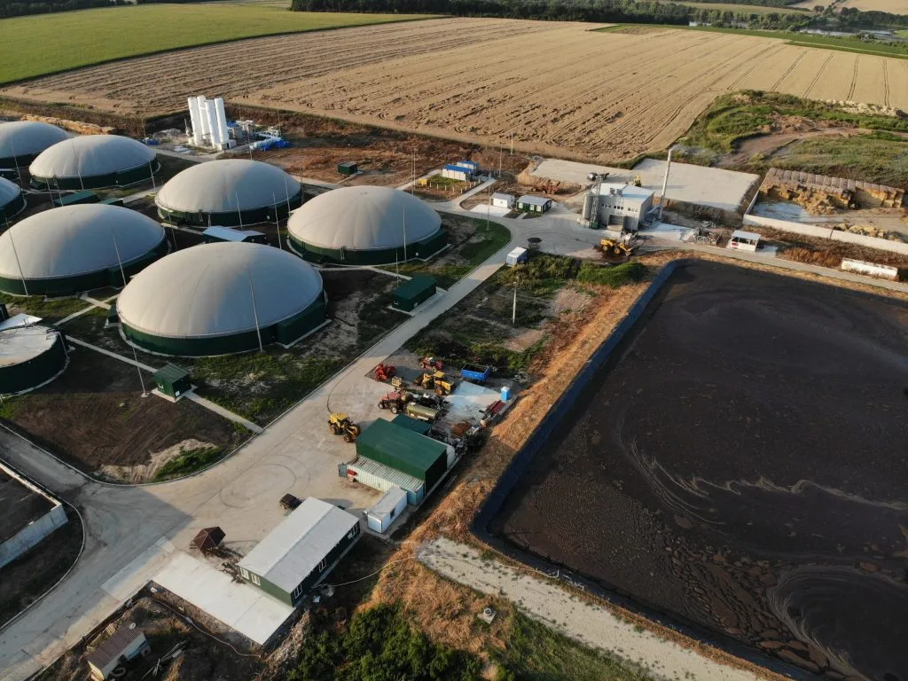 Luftaufnahme einer Biogasanlage mit Fermentern, Gärrestlager und Betriebsfahrzeugen