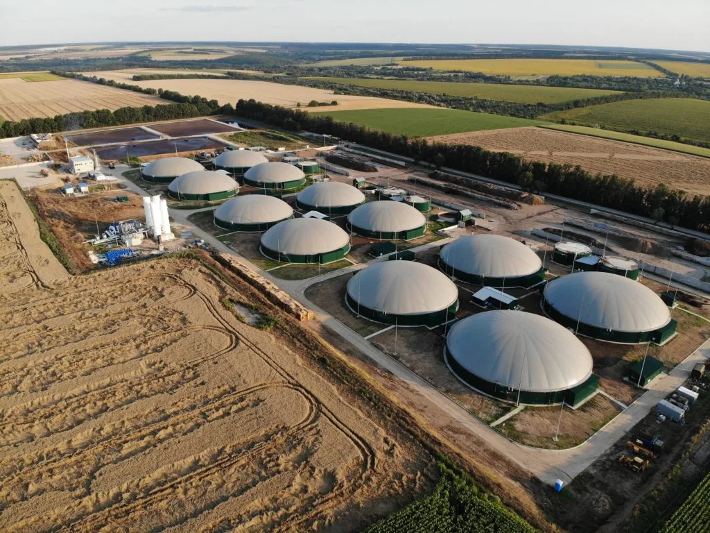 Luftaufnahme einer Biogasanlage mit mehreren Fermentern inmitten landwirtschaftlicher Felder