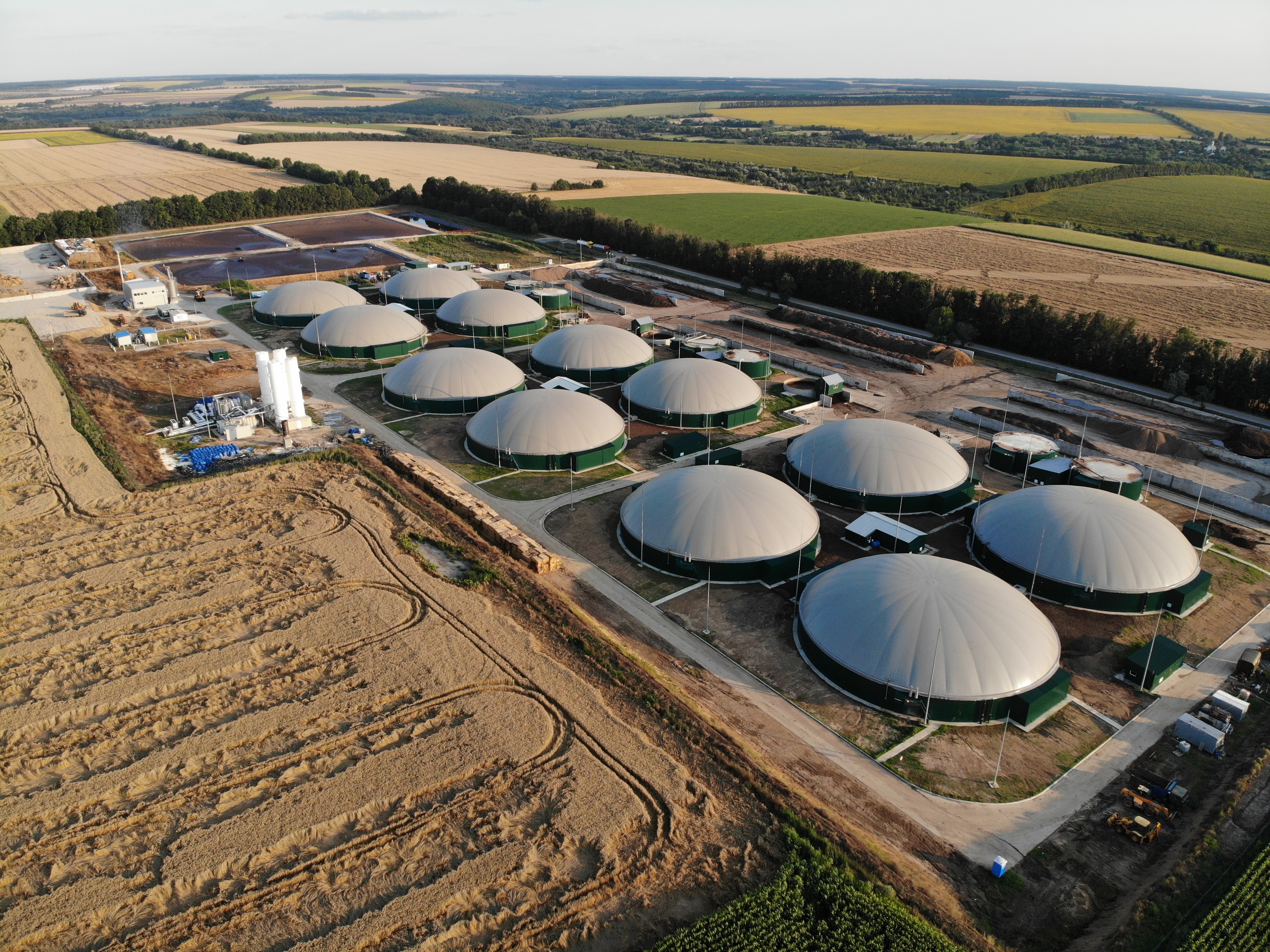 Luftaufnahme einer Biogasanlage mit mehreren Fermentern inmitten landwirtschaftlicher Felder